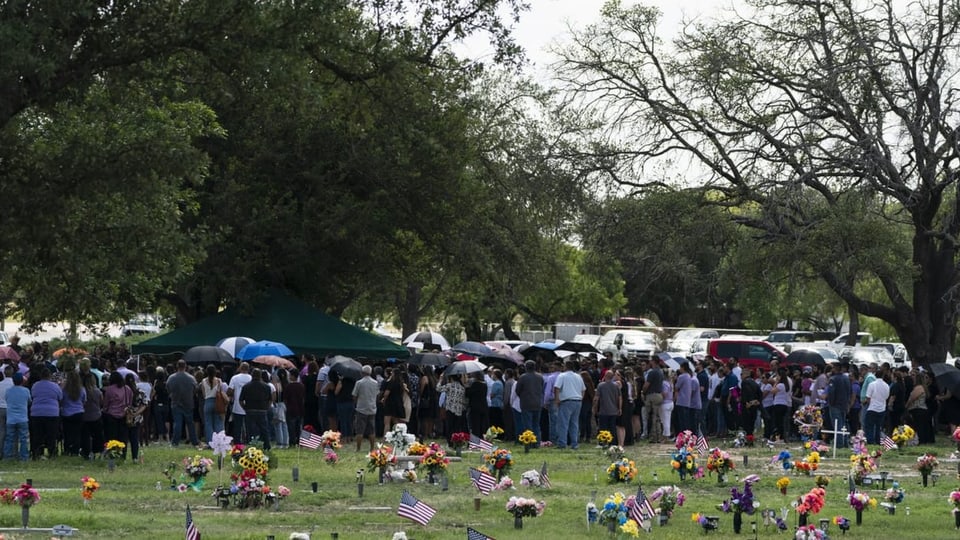 Eine Menschenmenge auf einem Friedhof.