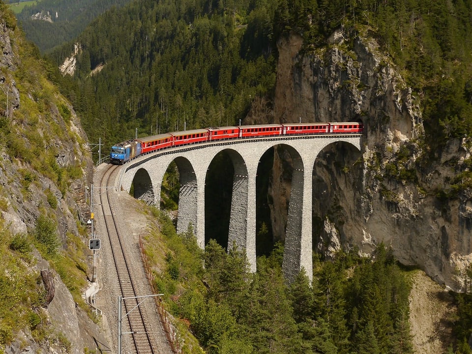 Ein Zug der Rhätischen Bahn überquert auf einem Viadukt eine Schlucht.