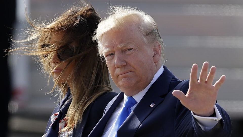 Trump und seine Frau gehen an Kamera vorbei, Trump winkt.