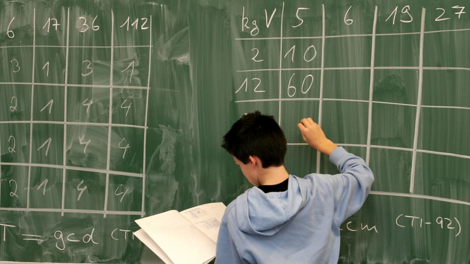 Ein Schüler löst an einer Tafel in der Schule eine mathematische Aufgabe.