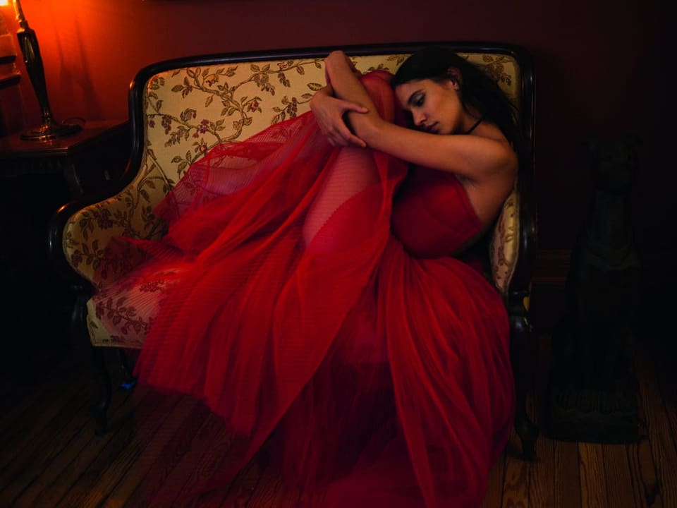 Frau liegt im roten Kleid auf einem Sofa