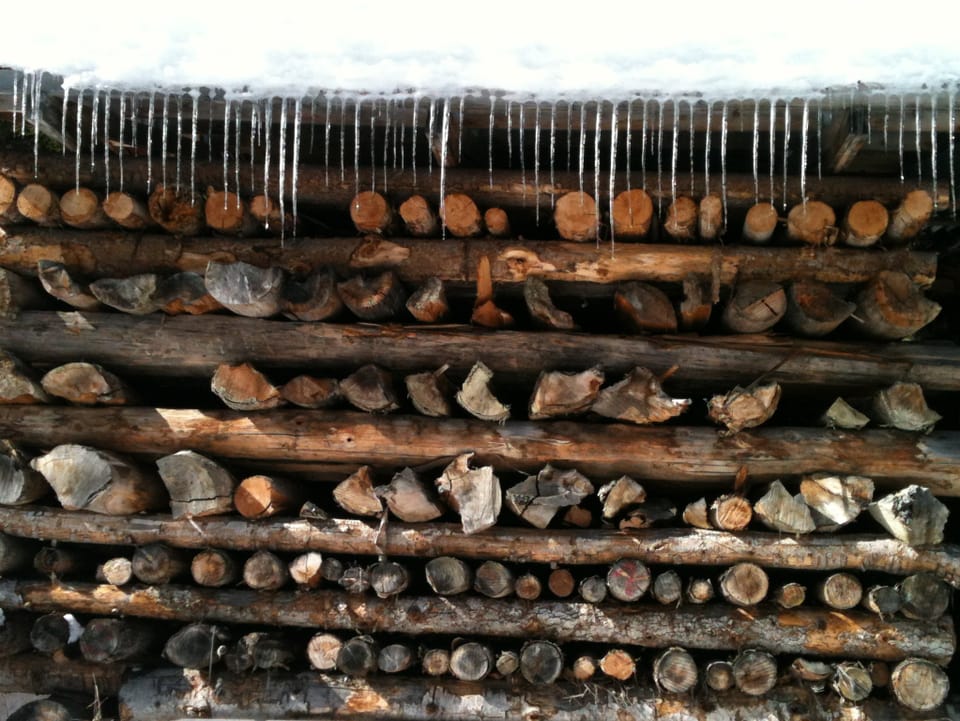 Holzbeide und am Dach der Holzbeige viele Eiszapfen.
