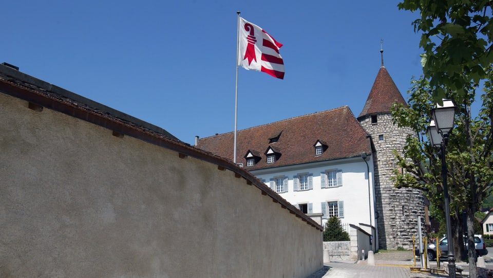 Totale auf ein Gebäude mit einem Turm und einer Jura-Flagge.