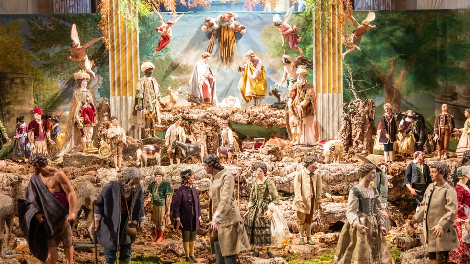 Eine Krippe mit vielen Figuren, sehr farbig. Im Zentrum Maria, Josef und das Jesuskind. Rundherum viele weitere Figuren.