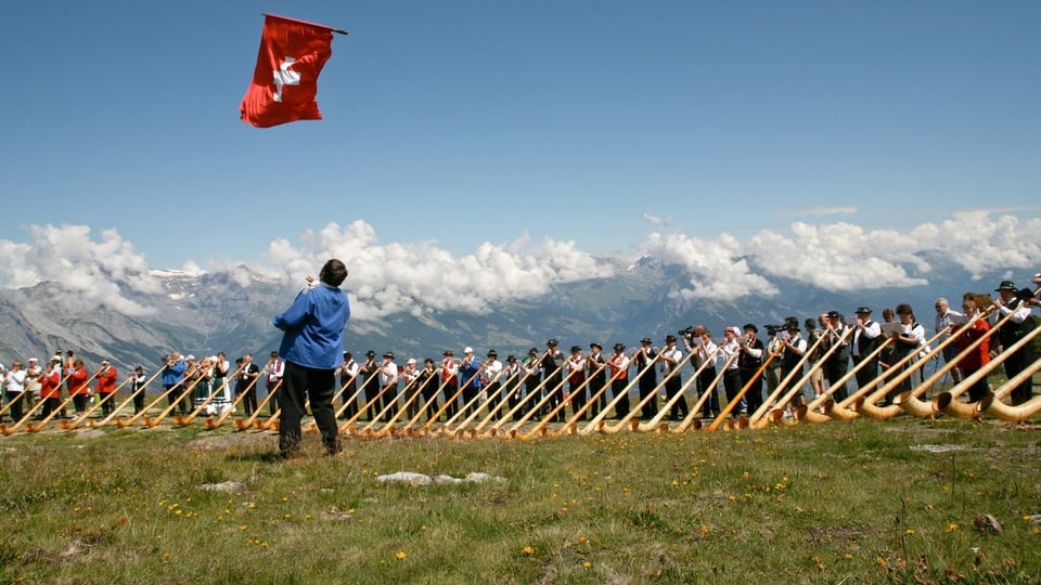 Menschen mit Alphorn und Schweiz-Fahne.