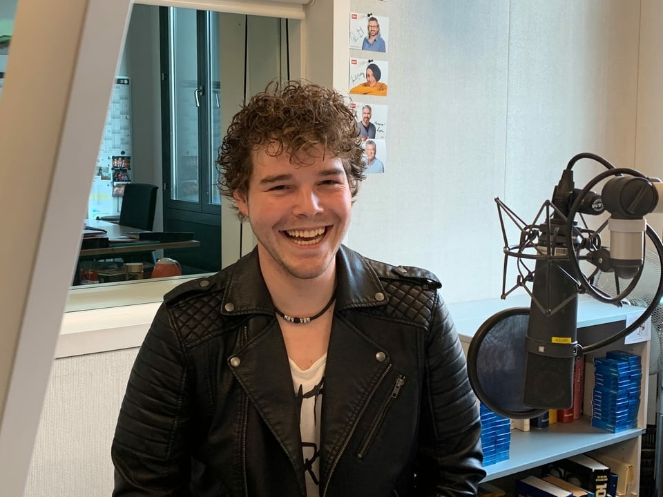 Junger Mann mit Lederjacke im Radiostudio.