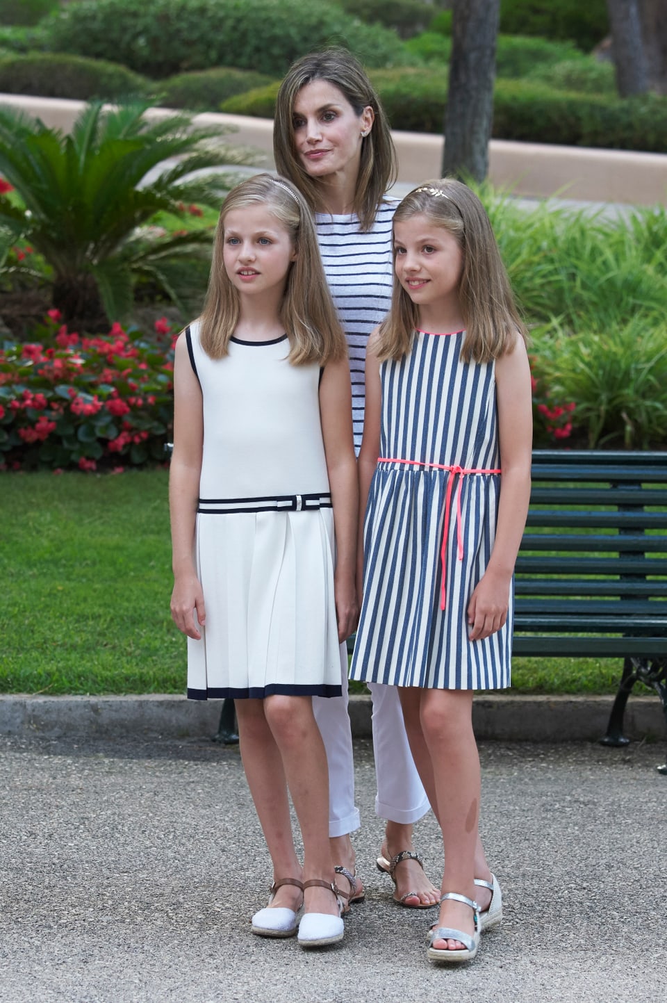 Königin Letizia steht mit ihren Töchtern im Garten.