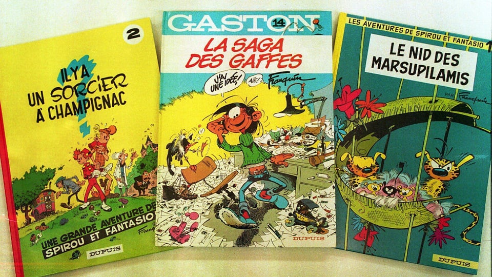 Drei französische Comicbücher aufgefächert dargestellt.