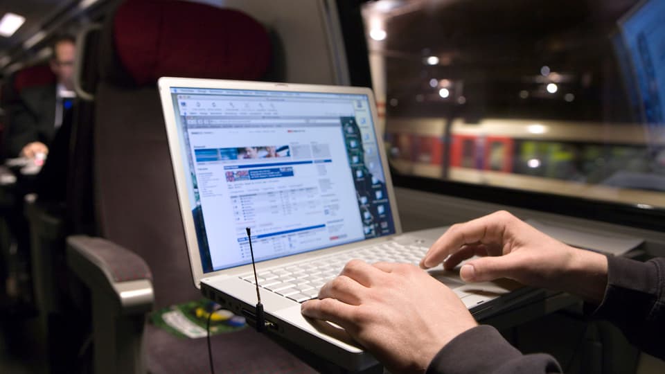 Das Bild zeigt einen Zugreisenden mit einem Laptop.
