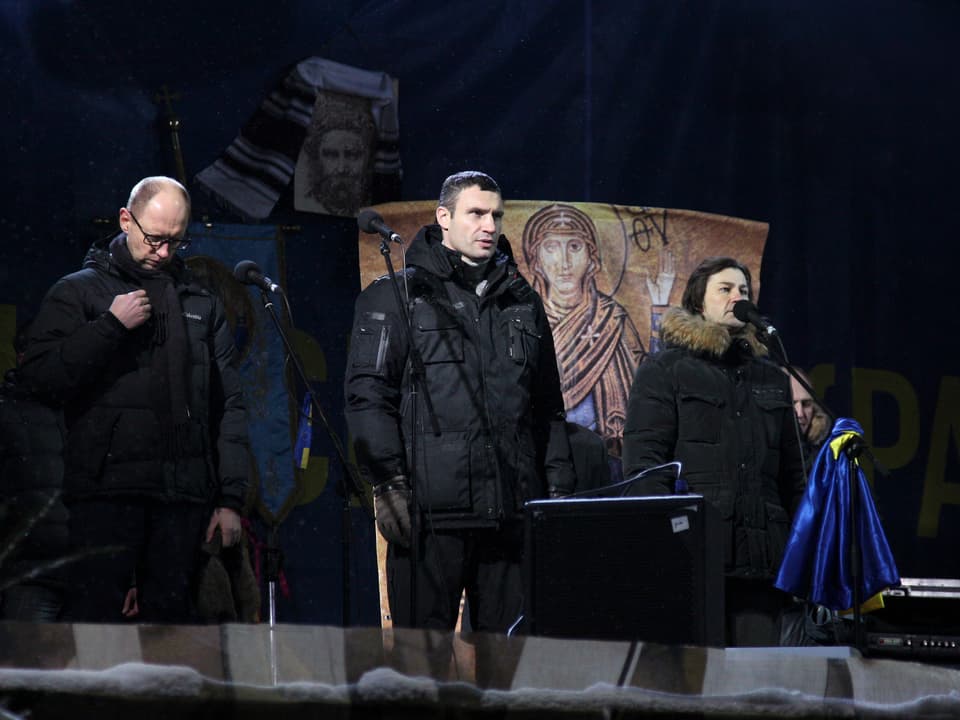 Jazenjuk, Klitschko und eine Frau auf einer Bühne, die Frau spricht in ein Mikrofon.