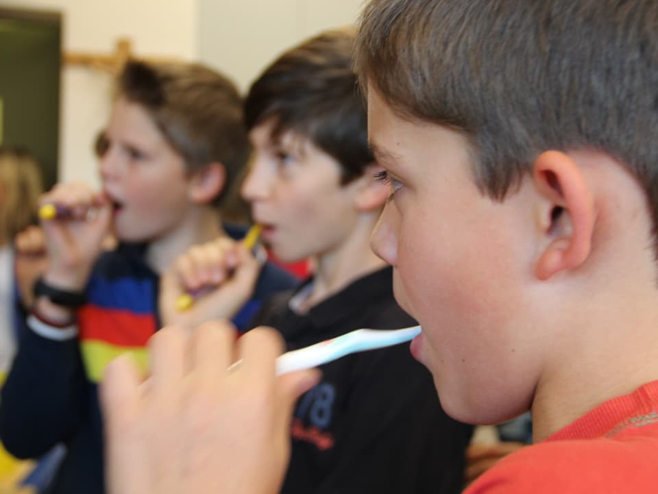 Daniele und zwei seiner Klassenkameraden putzen sich die Zähne.
