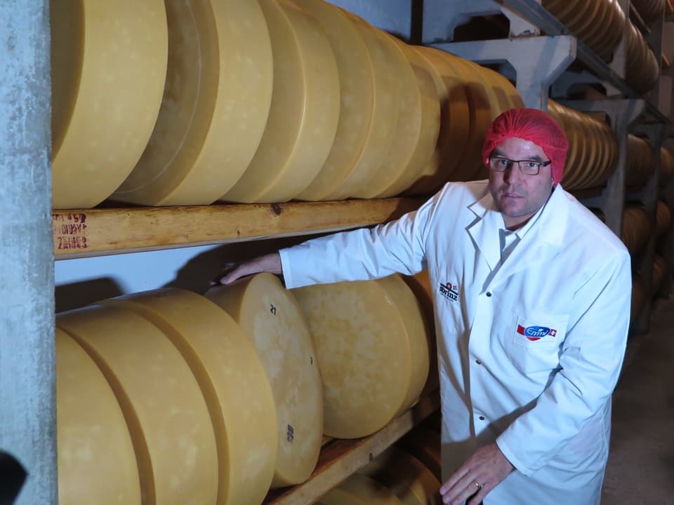 Sbrinz-Geschäftsleiter Stefan Heller mit roter Plastikhaube in einem Käsekeller. 
