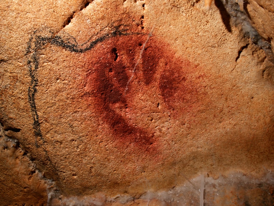 Rotes Handnegativ, daneben die angefangene Skizze eines Mammuts. 