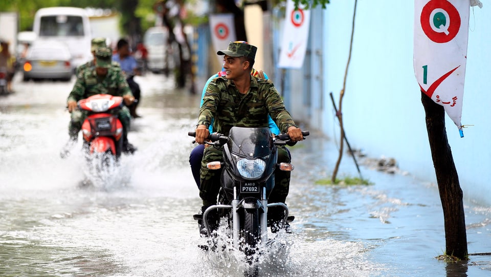 Soldaten fahren auf Motorrädern auf einer überfluteten Strasse in Male.