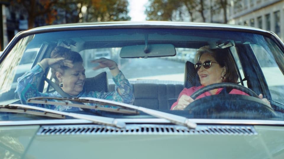 Zwei Frauen sitzen in einem fahrenden Auto und unterhalten sich.