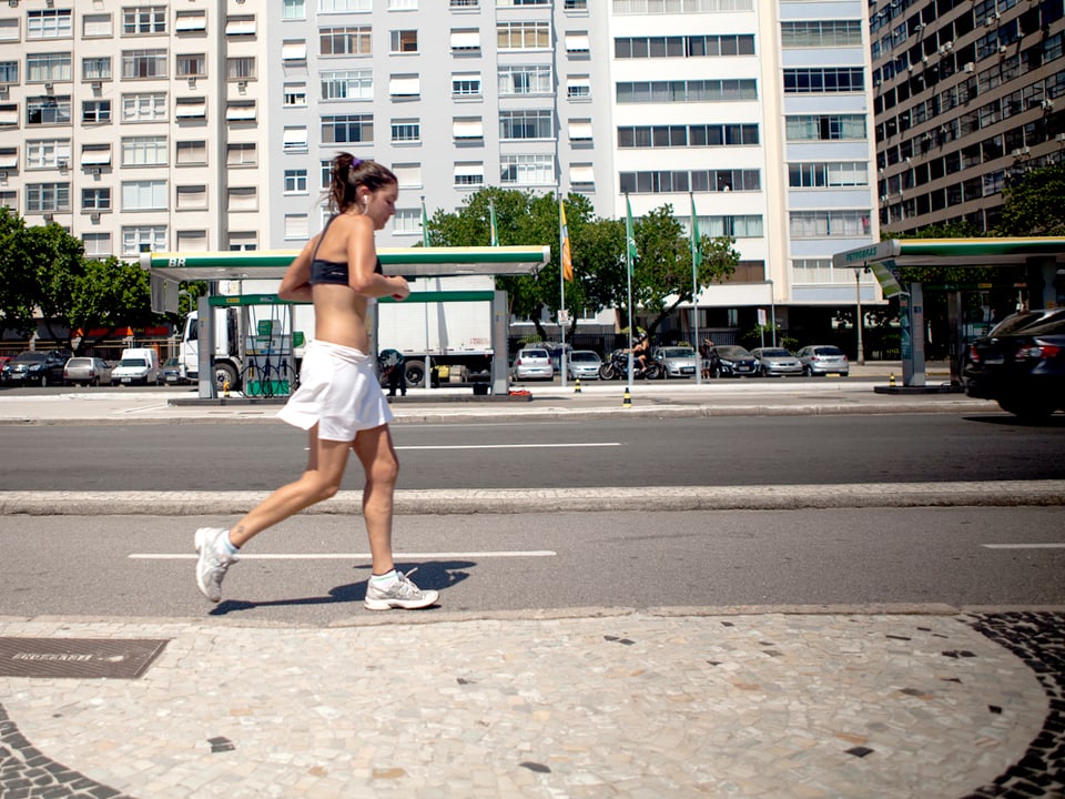 Eine junge Frau joggt der Strasse entlang.