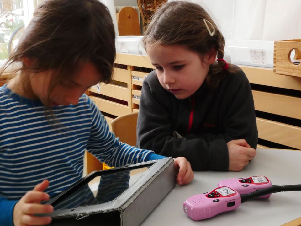 Zwei Mädchen schauen auf einen Tablet-Computer.
