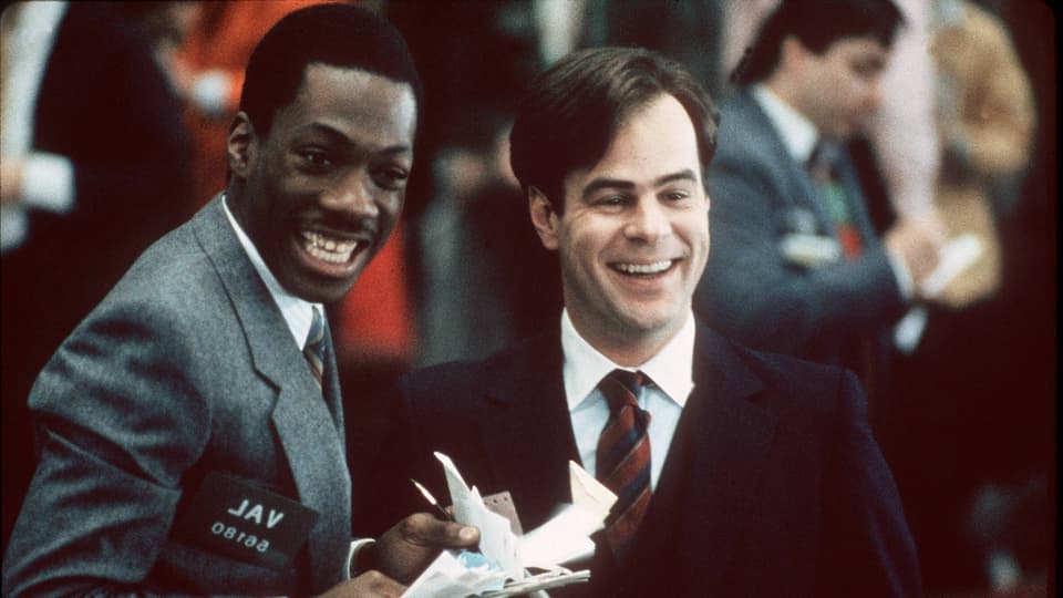Film-Still aus «Trading Places»: Murphy und Dan Aykroyd stehen lachend nebeneinader.