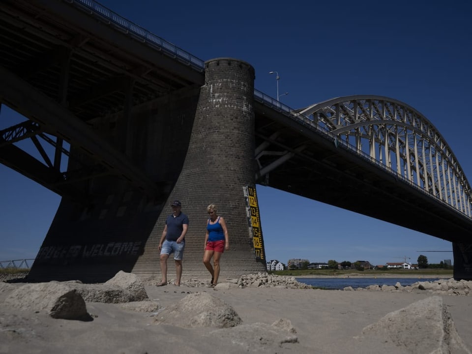 Brücke, man sieht Menschen spazieren, der Wasserpegel ist sehr niedrig.