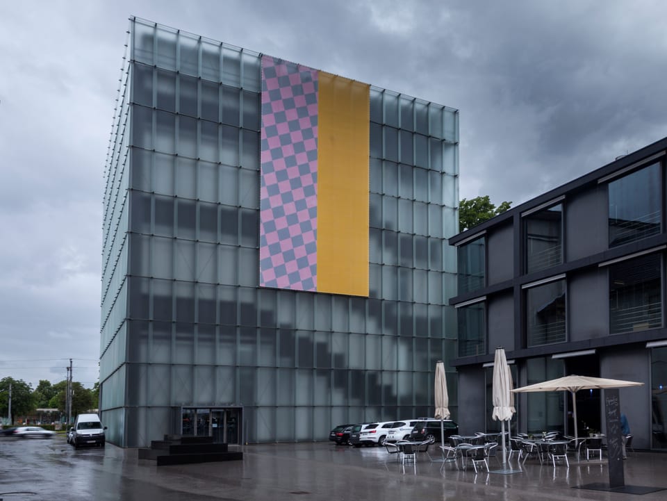 Das Kunsthaus Bregenz. An seiner Fassade hängt eine farbige Flagge.