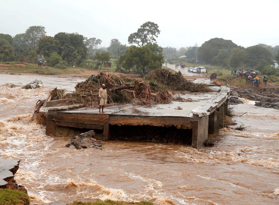 Mann steht auf einer halb weggeschwemmten Autobrücke.