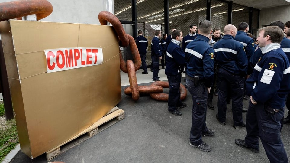 Wärter demonstrieren vor dem Genfer Gefängnis Champ-Dollon neben einem grossen Vorhängeschloss. Darauf steht «Complet»