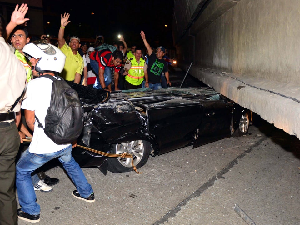 Menschen in Guayaquil versuchen ein eingeklemmtes Erdbebenopfer in einem Auto zu retten.