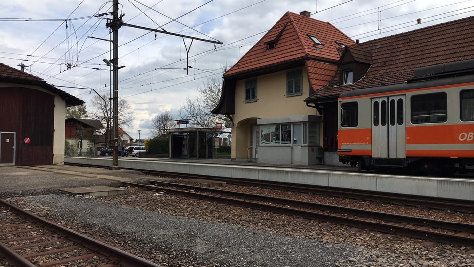 Bahnhofgebäude mit altem, orangem Zug auf einem Abstellgleis.