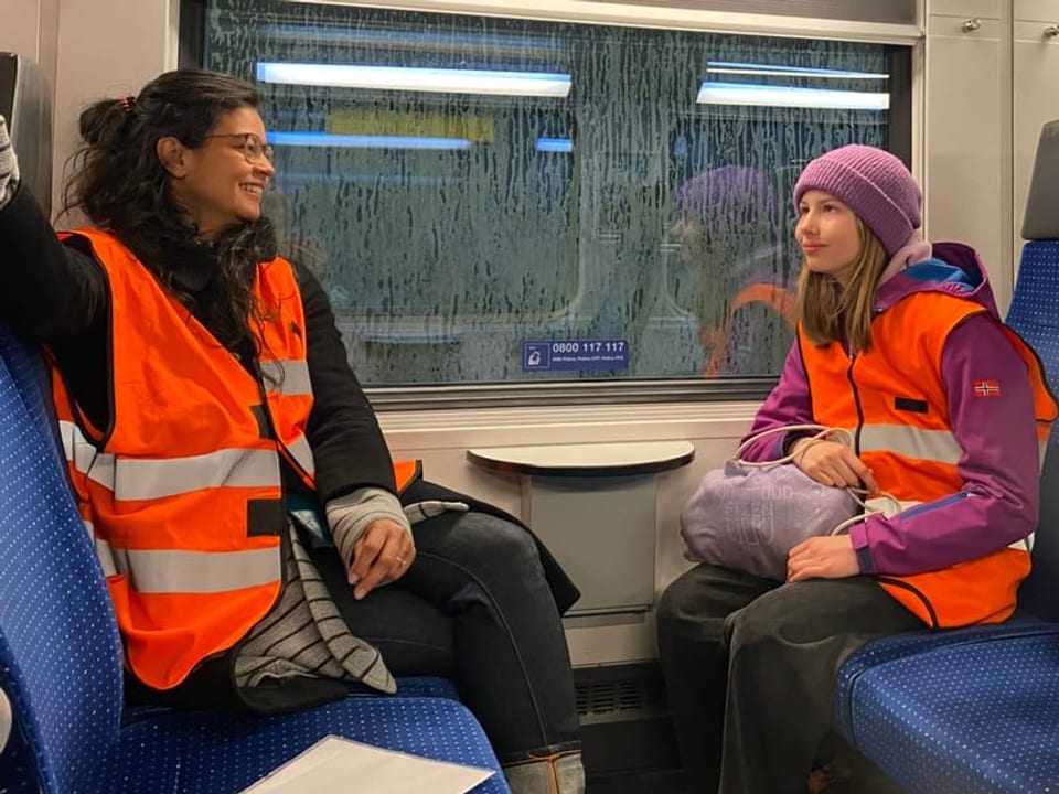 Marie Lotta und Julia sitzen wie gewohnt auf den Sitzen im Zug, aber die Scheiben sind draussen klitschnass. 