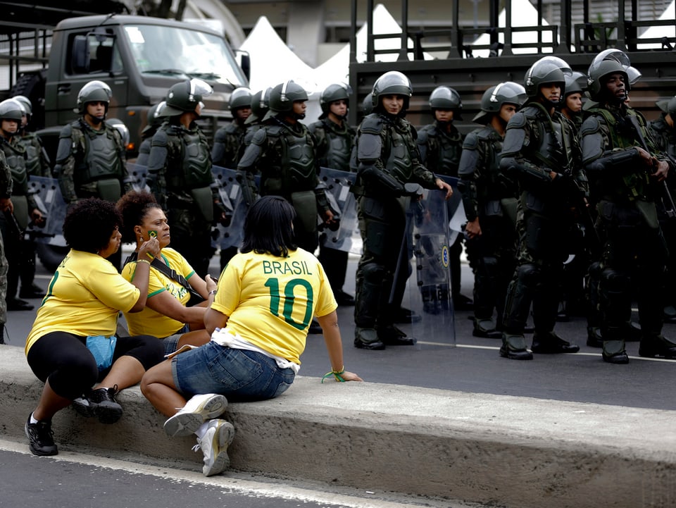 Bewaffnete Polizisten im Hintergrund. Vorne weibliche Brasilien-Fans.