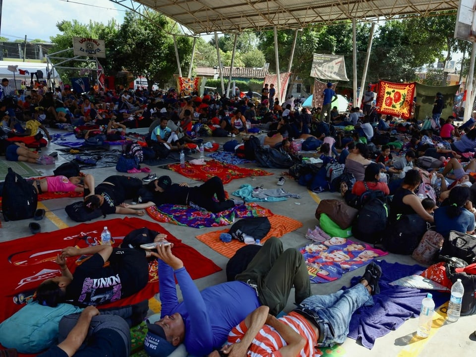 Migrantinnen und Migranten ruhen sich auf einem öffentlichen Platz aus, bevor sie ihre Reise durch Mexiko fortsetzen. 