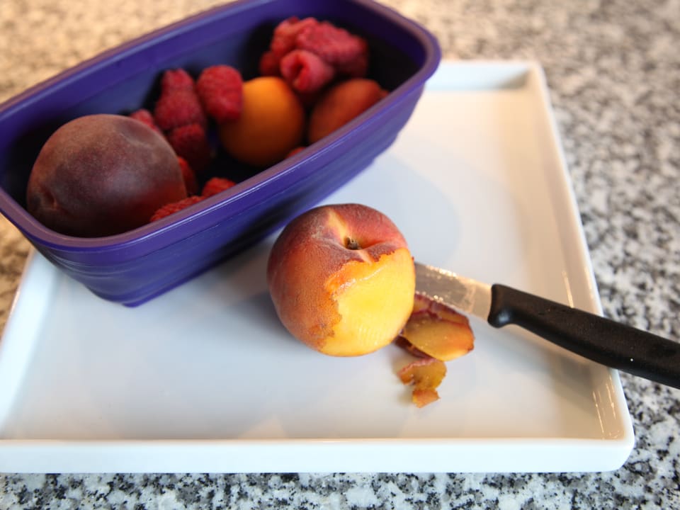 Pfirsich wird mit einem Messer in kleine Stücke geschnitten. 