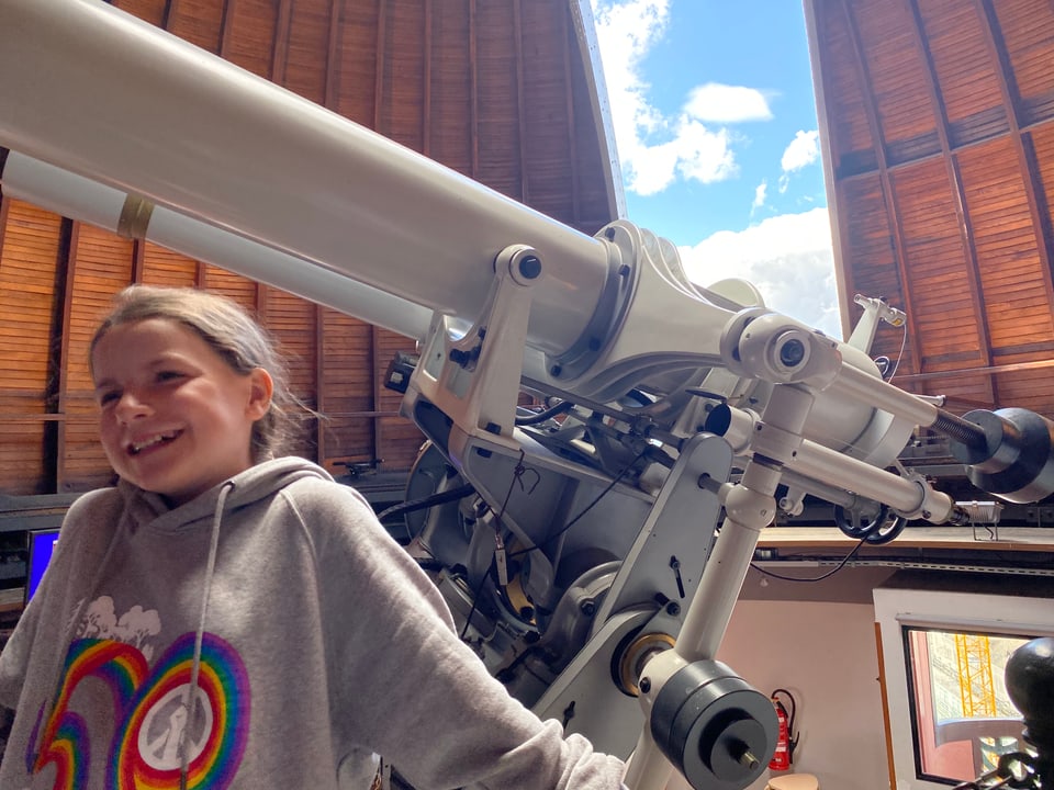 Elin steht glücklich vor dem Teleskop