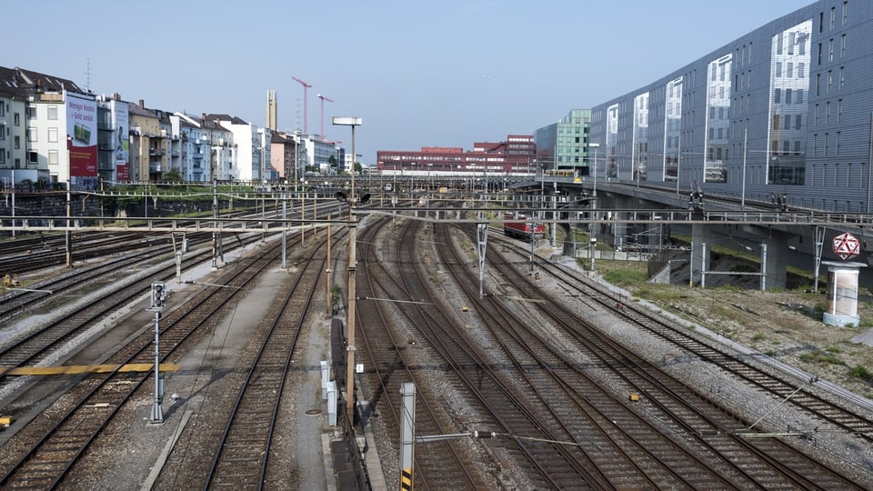 Blick auf mehrgleisigen Bahnhofsbereich mit umliegenden Gebäuden.
