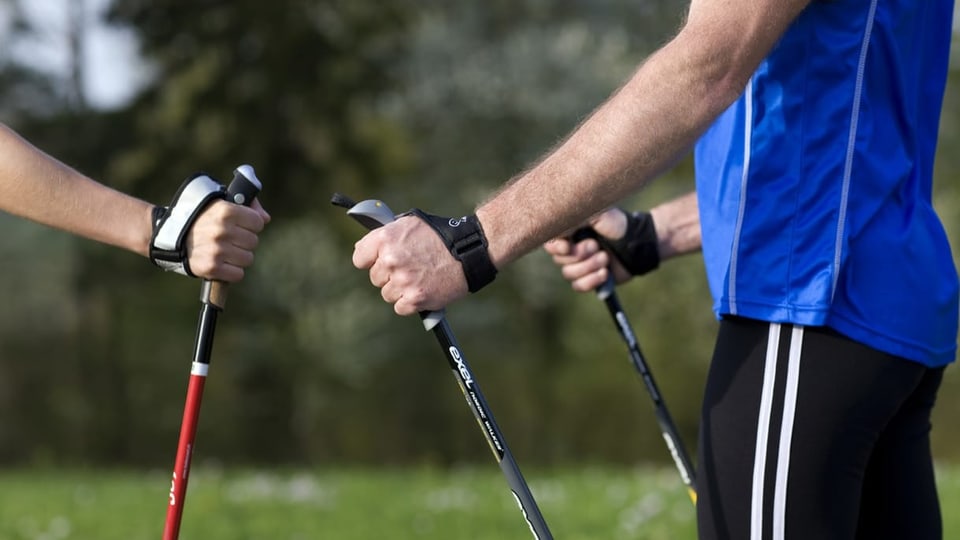 Auf dem Bild sind zwei Menschen mit Nordic Walking Stöcken zu sehen.