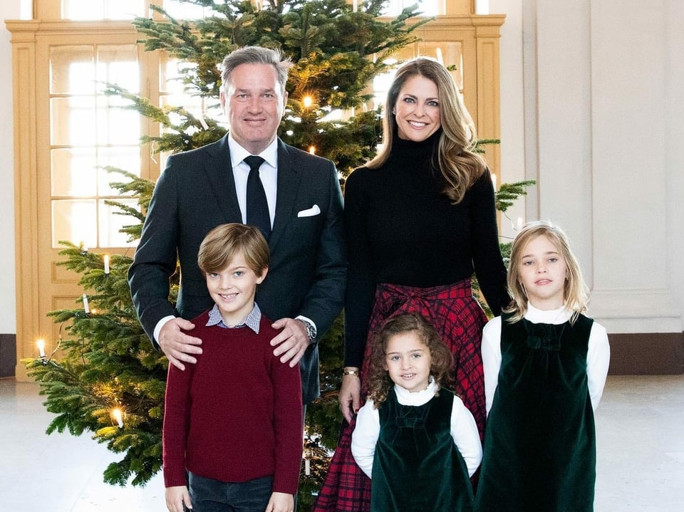 Mann und Frau mit drei kleinen Kindern, festlich gekleidet, vor einem Tannenbaum