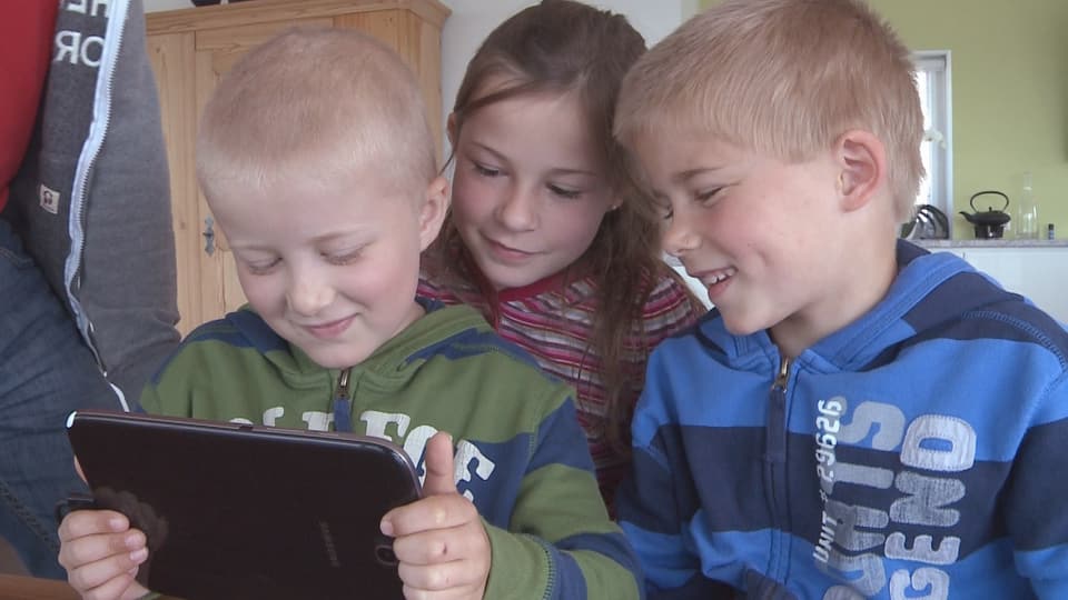 Drei Kinder sitzen vor einem Tablet.