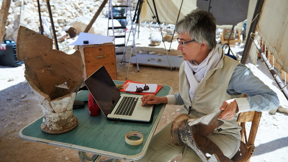 Susanne Bickel arbeitet am Computer. Sie ist an einem Ausgrabungsort.