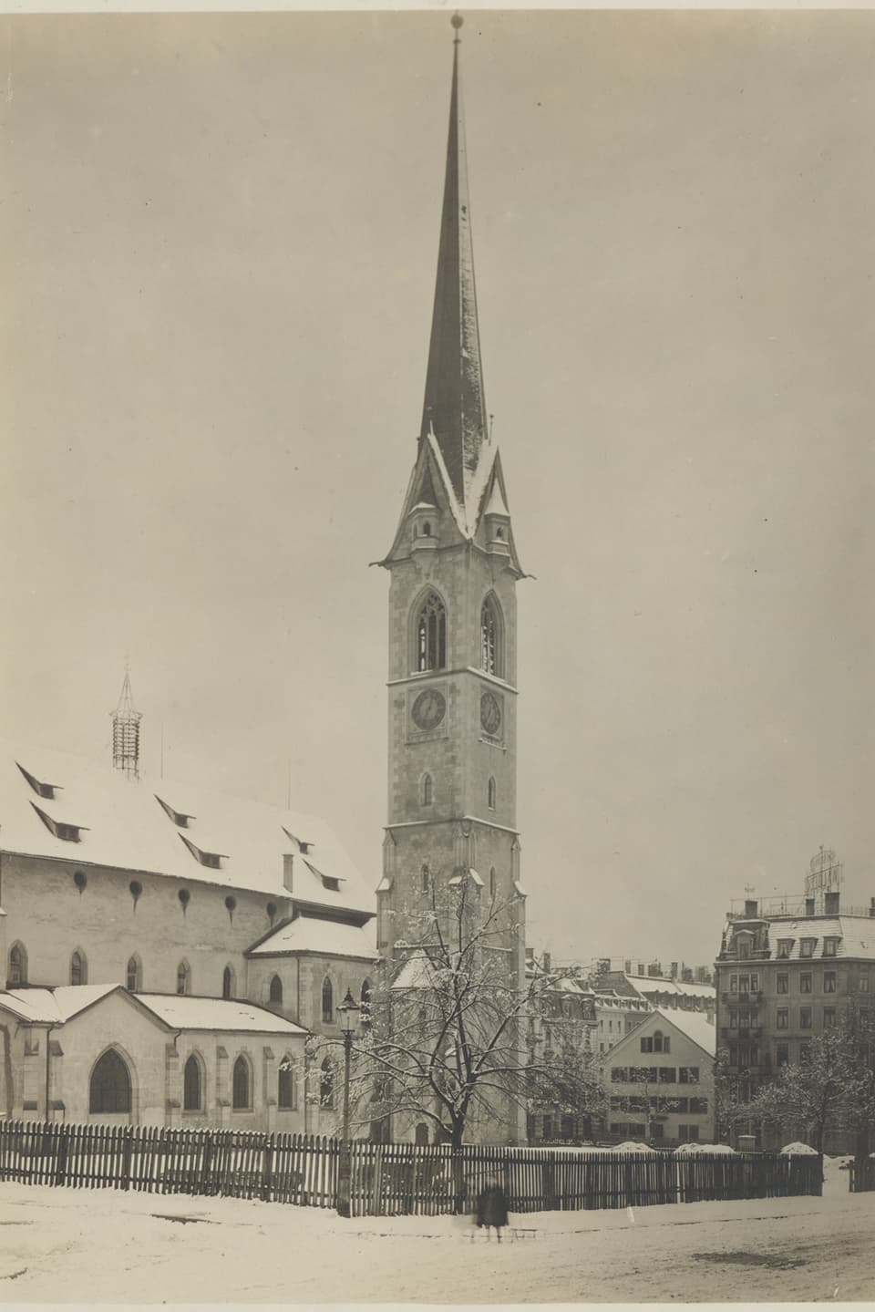Ein Kirchturm steht in einer verschneiten Landschaft. 