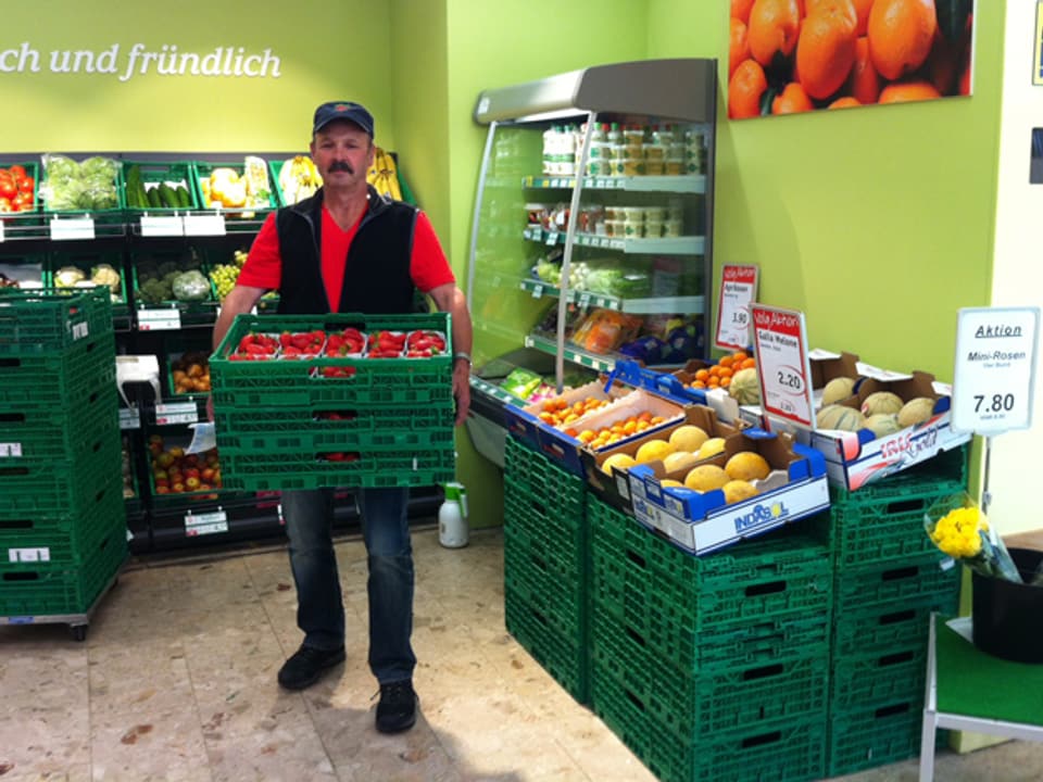 Hans-Ulrich Lüscher mit einer Palette Erdbeeren im Laden.