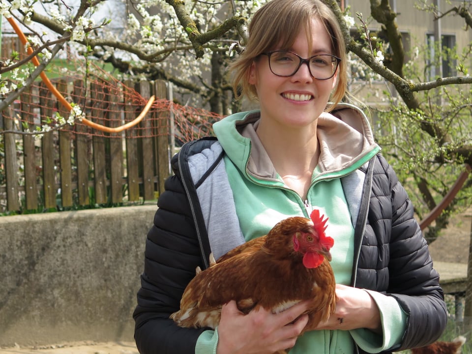 Junge Frau mit Huhn auf Arm