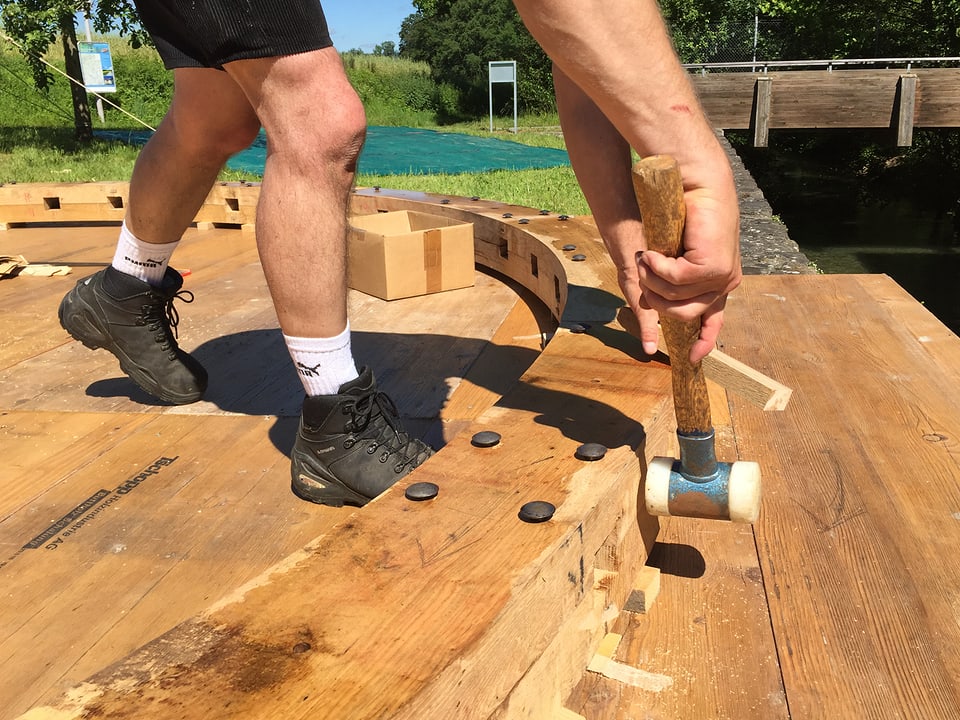 Mann klopft mit Hammer auf Holz