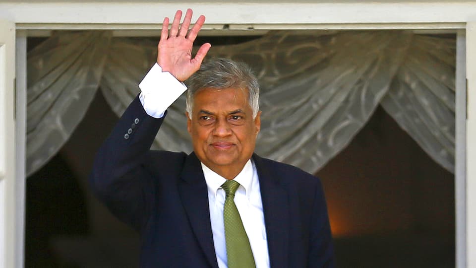 Der neue Ministerpräsident Sri Lankas, Ranil Wickremesinghe, steht am Fenster des Regierungspalastes und winkt.