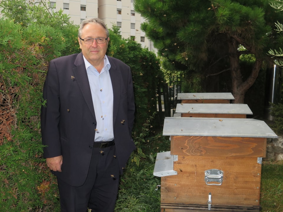 Marcel Maurer steht vor seinen drei Bienenhäuschen im Garten.