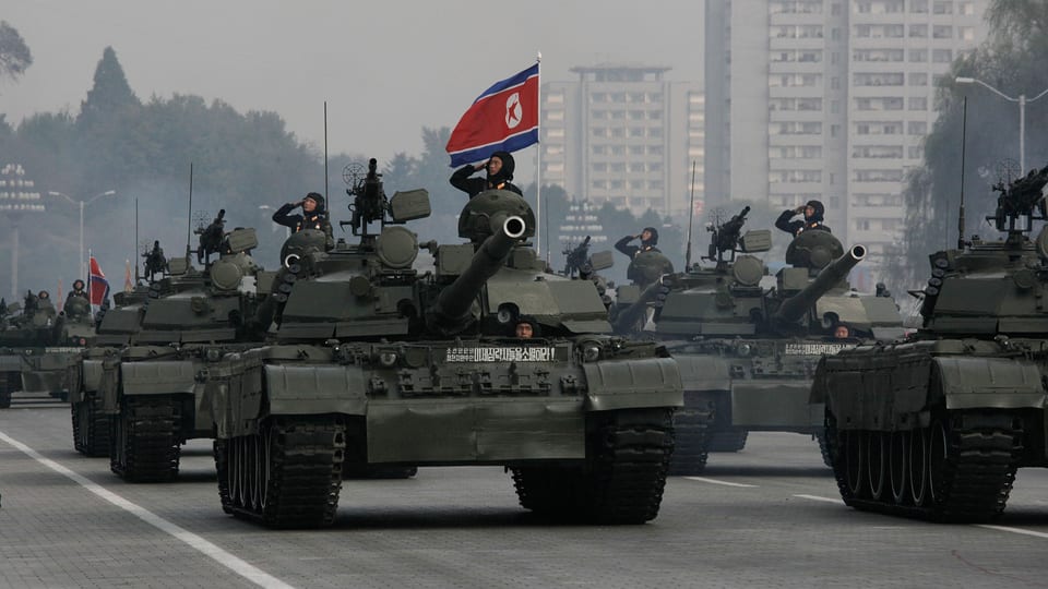 Panzer mit Soldat auf einer Militärparade in Nordkorea. Im Hintergrund die nordkoreanische Flagge.