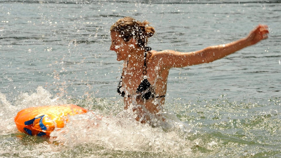Eine Frau springt in Rhein bei Basel. Das Wasser spritzt.