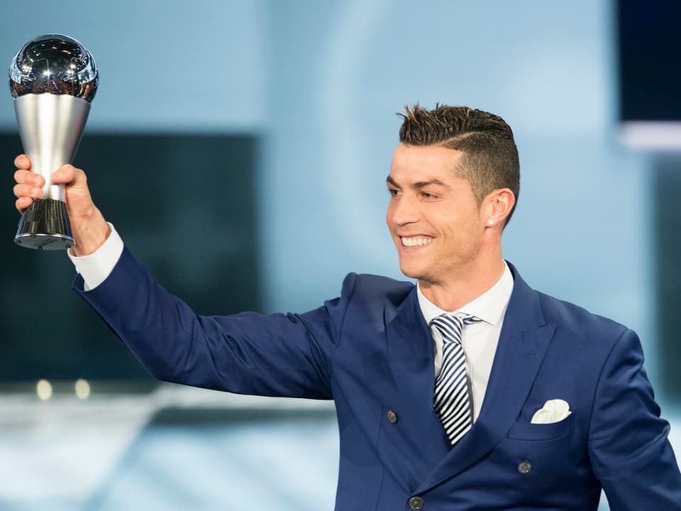 Der portugiesische Fussballer Cristiano Ronaldo hält eine Trophäe in die Luft.