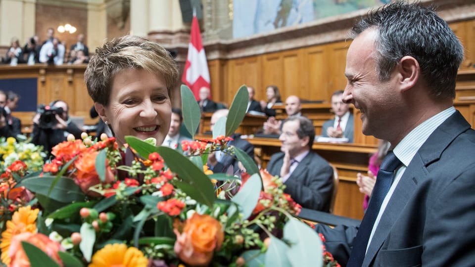 Sommaruga hinter einem Blumenstrauss, zu ihrer Rechten: Nationalratspräsident Stéphane Rossini von der Seite.