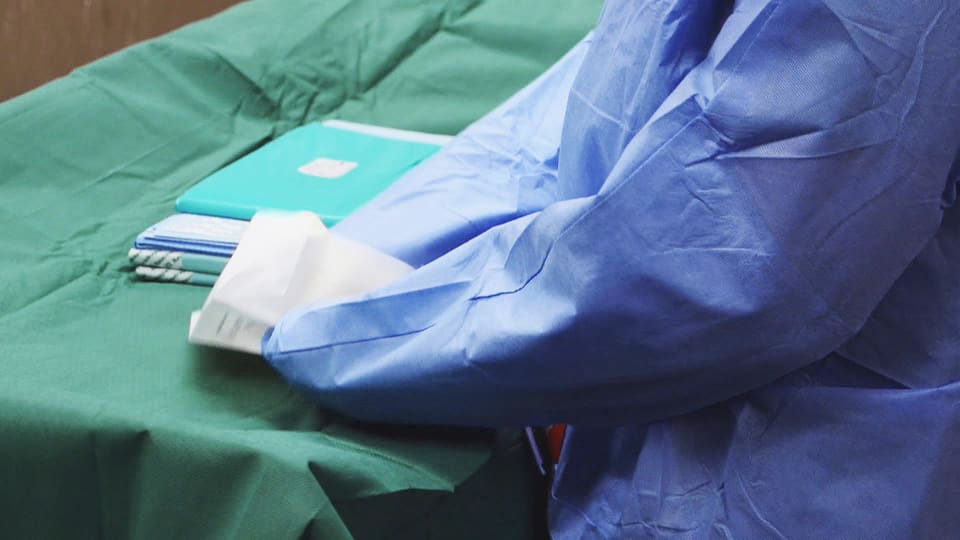 Eine Person in OP-Kittel packt sterile Instrumente aus.