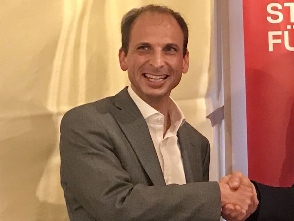 Michael Fuchs mit Anzug und weissem Hemd schüttelt die Hand eines Kollegen an der Nominationsversammlung der SP Schwyz.